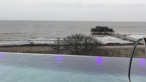 En infinitypool med utsikt över havet och en brygga.