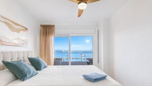A bedroom with a large bed, a ceiling fan, a view of the sea, and a balcony. - MONACO 1 A Roses (Rosas / Roses)