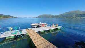 Une jetée en bois s’étendant dans une étendue d’eau calme, avec des bateaux amarrés à son extrémité.