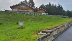 Une colline où se trouvent deux chalets en bois portant l’inscription « Appartements de location pour les vacances ».
