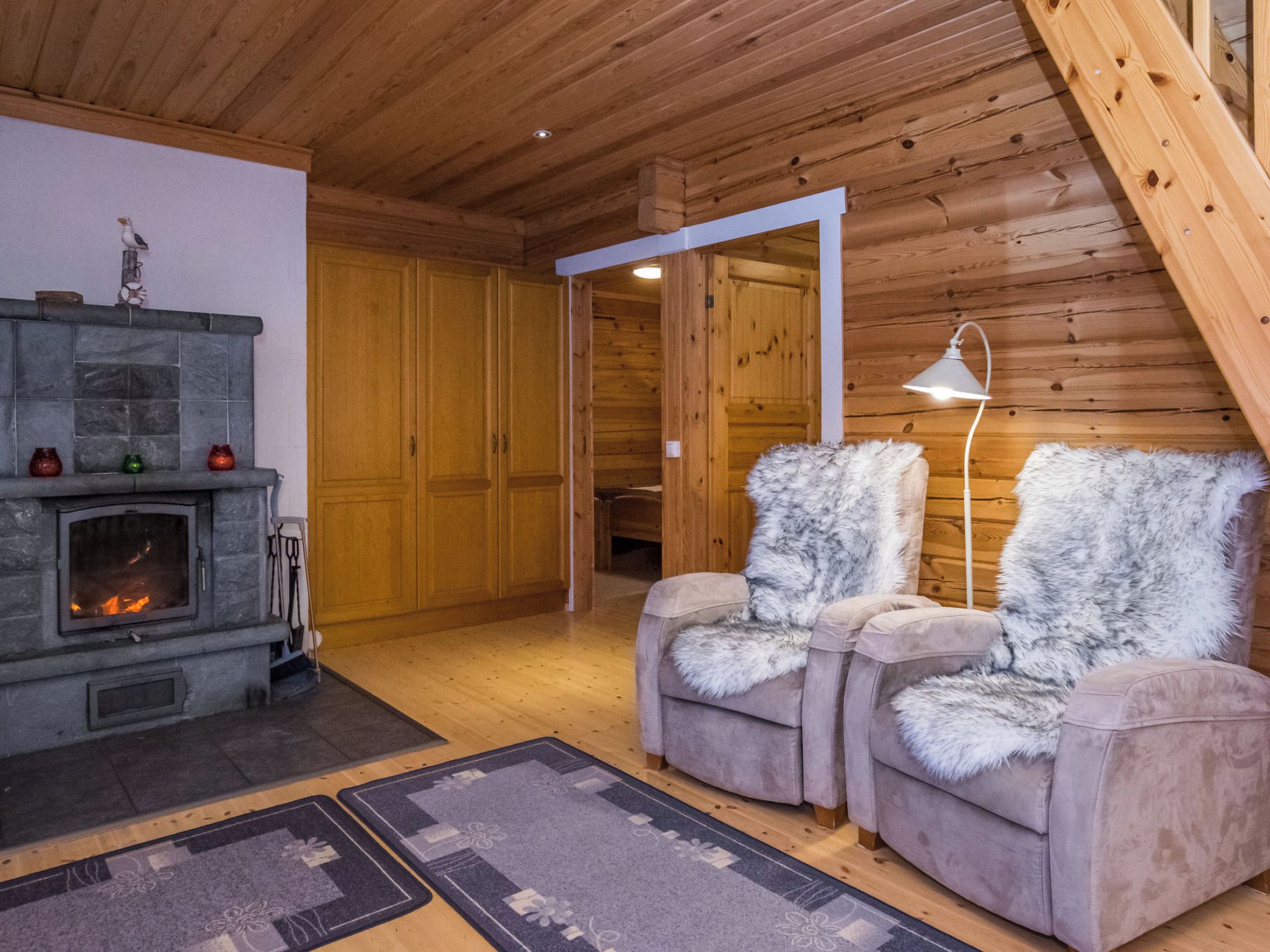 Un interior de cabaña acogedor, con chimenea de piedra, dos sillones cómodos y techo de madera.