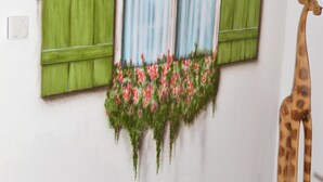 A room with a wooden bench, a window with green shutters, a hanging flower basket, and a giraffe decoration. - A holiday house / apartment with a difference - with a sauna in the living area.  (Löbnitz)