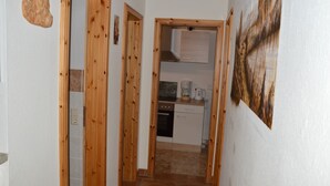A narrow hallway with wooden doors leading to a kitchen area. - A holiday house / apartment with a difference - with a sauna in the living area.  (Löbnitz)