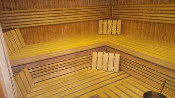 A sauna with wooden benches and a metal bucket.