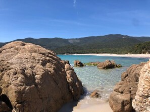 A coastal landscape with large rocks, clear turquoise water, and a sandy beach. - Villa gulf of valinco 120 m2, sea and mountain, air-conditioned 7 mn from the beaches (Sollacaro)