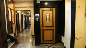 A hotel corridor with a wooden door, tiled floor, and a staircase on the left. - Hotel Park View Mumbai (Mumbai)