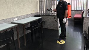 A person standing in an outdoor area with a table and chairs, a wall-mounted fan, and a fire extinguisher. - Hotel Park View Mumbai (Mumbai)
