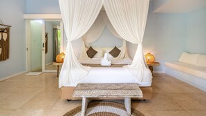 A bedroom with a canopy bed, bedside lamps, and a bench.