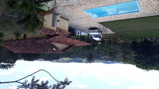 Une maison avec une piscine, un toit en tuiles et une voiture garée sous un abri.