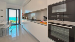 A modern kitchen with a Siemens oven, a built-in sink, and a view of the ocean through a glass door. - Apartment Astrolab (Funchal / Madeira - Portugal)