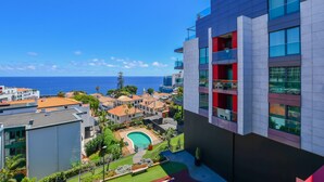 A modern building with a pool, surrounded by greenery and a view of the sea. - Apartment Astrolab (Funchal / Madeira - Portugal)
