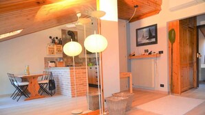 Una cocina acogedora con una isla de ladrillo, techo de madera y un comedor con sillas y mesa.