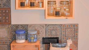 Una cocina con estantes de madera que sostienen frascos y un tostador.