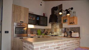 Una cocina con isla de ladrillo, armarios de madera, electrodomésticos de acero inoxidable y salpicadero de azulejos.