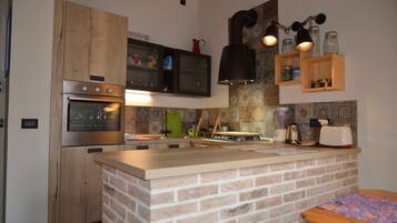Une cuisine dotée d’un îlot central en briques, de meubles en bois, d’appareils électroménagers en acier inoxydable et d’un dosseret carrelé.