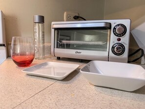 Een oven, een vaatwasser, kookgerei, borden en bestek, keukenrol
