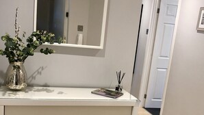 A modern bathroom with a white vanity, a mirror, two wicker baskets, and a vase with greenery.
