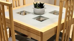 A dining table with a glass top, surrounded by wooden chairs with cushioned seats.