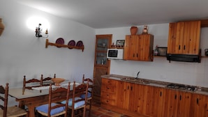 A kitchen with wooden cabinets, a microwave, a sink, and a dining table with chairs.