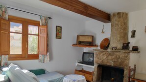 A cozy room with a stone fireplace, a television, and a bed with striped bedding.