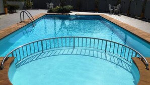 A rectangular swimming pool with a wooden deck and metal railings.