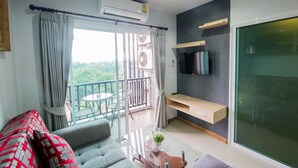 A modern living room with a balcony, a flat-screen TV, and a sliding glass door.