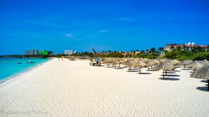 A beach with white sand, clear blue water, and thatched umbrellas. - 10% discount for weekly stay. 2 Bedrooms 2 Baths Condo in Eagle Beach Aruba! (Noord)