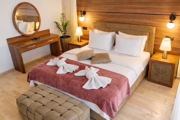 A hotel room with a bed, bedside tables, a mirror, a dresser, and a potted plant. - Capitol Suites (Skopje)