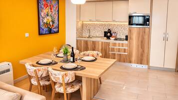 Una cocina moderna con microondas, un lavamanos y una zona de comedor con mesa y sillas de madera.