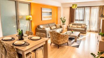 A modern living room with a dining area, two sofas, a coffee table, and a large window with curtains.