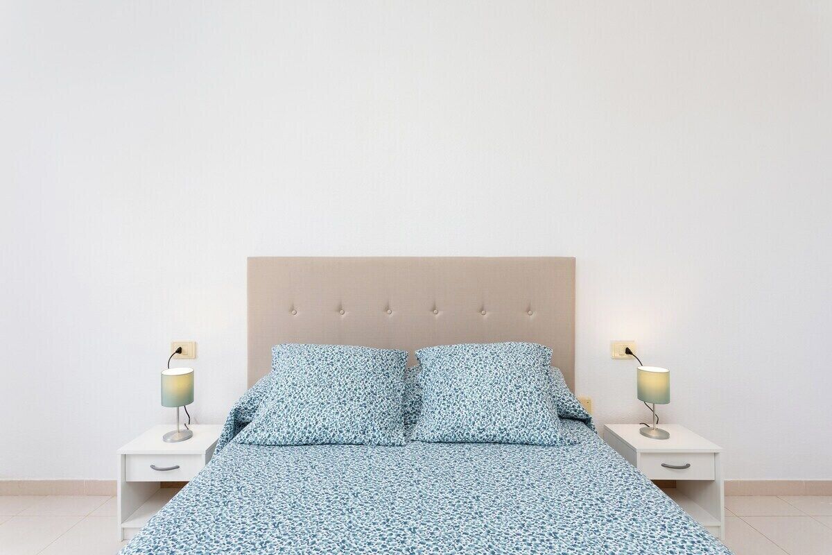 A bedroom with a bed, two bedside tables, and two lamps.