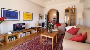 A living room with a television, bookshelves, a sofa, and a coffee table. - Lovely balcony in Musiciens, central Nice. (Nice)