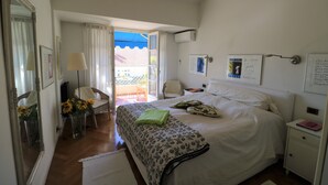 A bedroom with a bed, a nightstand, a chair, a mirror, and a window with curtains. - Lovely balcony in Musiciens, central Nice. (Nice)