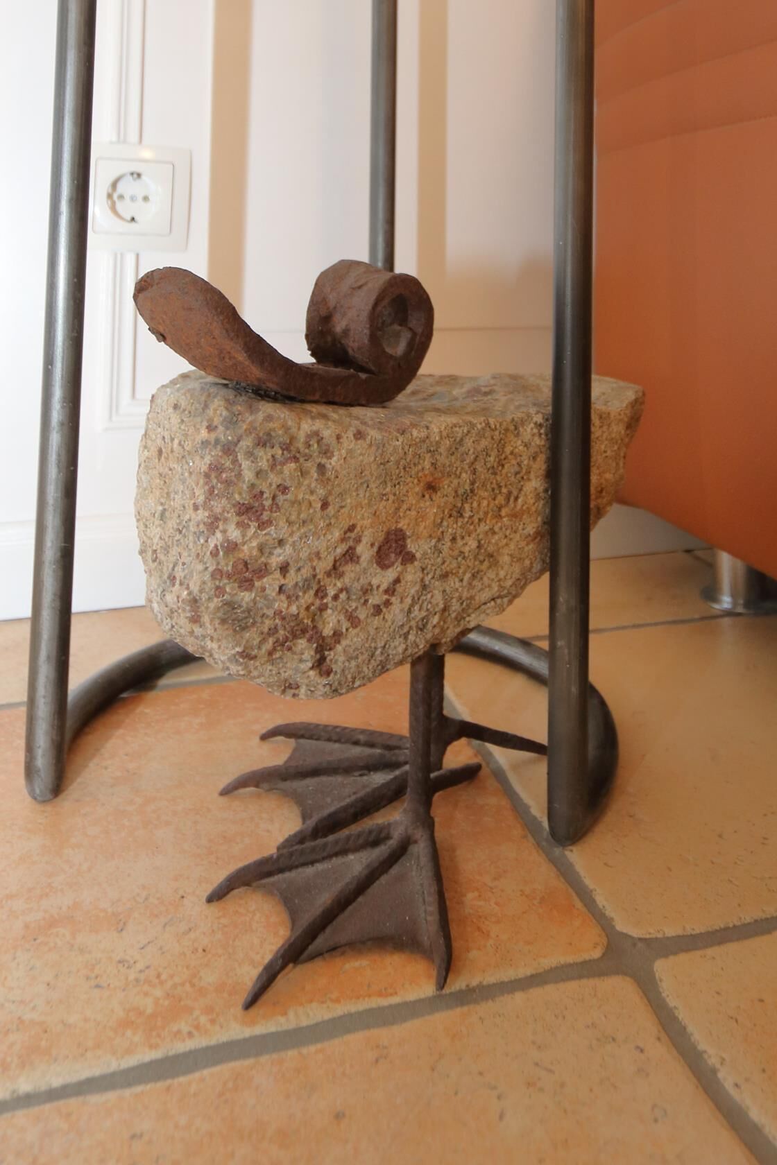 Un tabouret en métal au style rustique, doté d’une assise en pierre et d’un socle en métal décoratif.