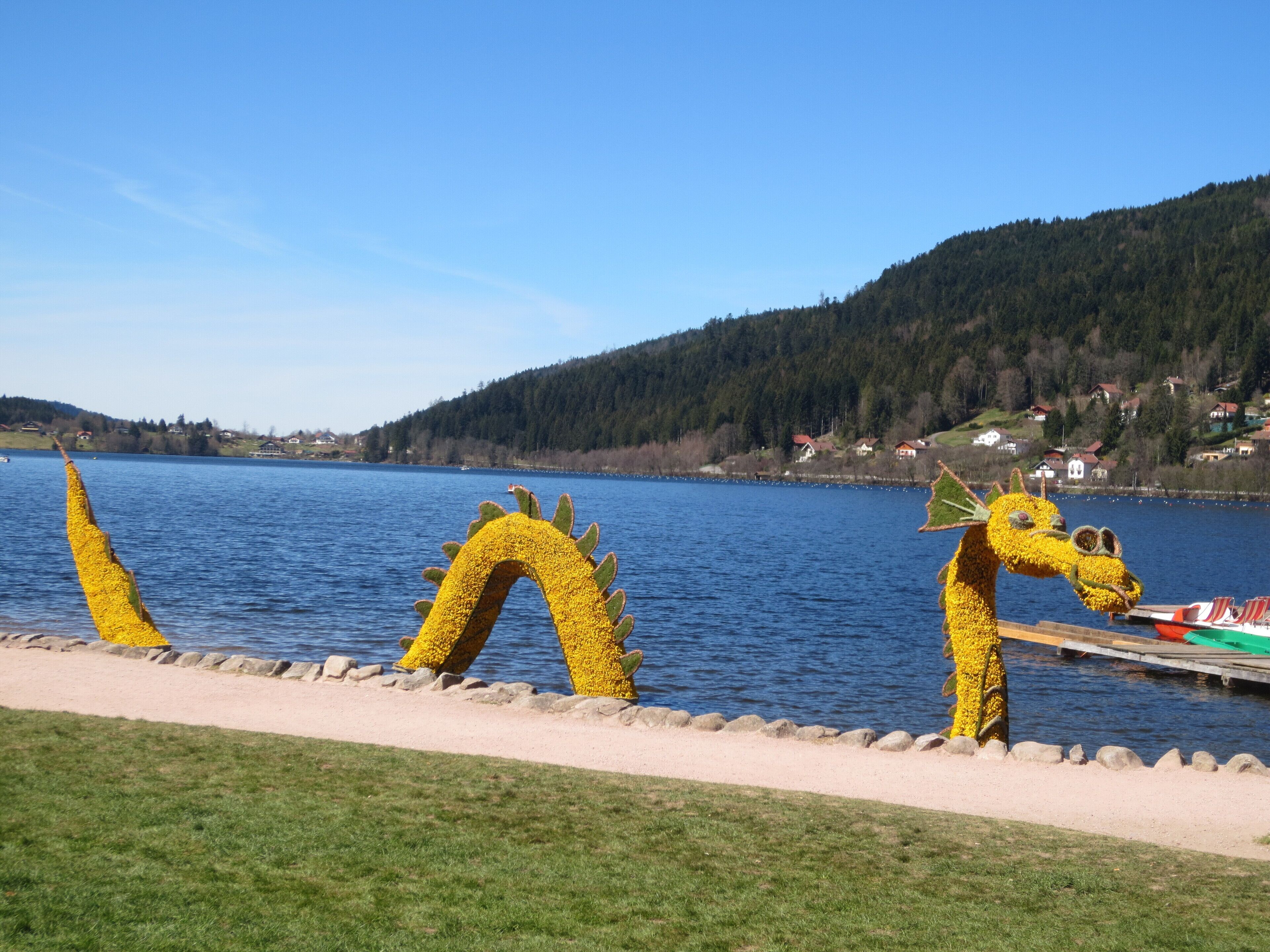A lakeside view with a row of yellow dragon sculptures along the shore.