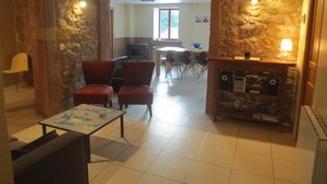 Un salon chaleureux avec des murs en pierre, une cheminée et un coin repas comprenant une table et des chaises.