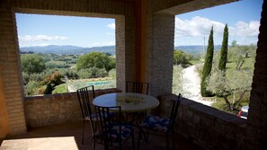 Enjoy a tranquil outdoor space with a round table and four chairs, overlooking a lush landscape with rolling hills and a clear sky.