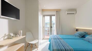 A hotel room with a bed, a desk, a chair, a TV, and a balcony with a view.