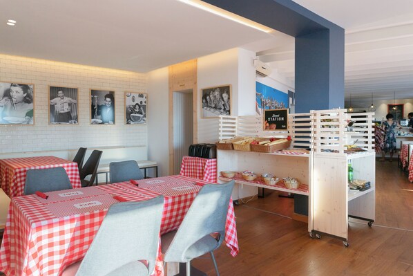 A restaurant interior with checkered tablecloths, chairs, a buffet cart, and wall-mounted pictures.