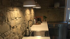 A kitchen with a stone wall, a white countertop, a stainless steel sink, and a stove. - Authentic stone house in the heart of Piedmont - with pool and wild views (Cessole)
