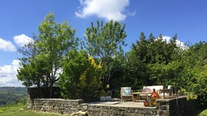 A stone patio with outdoor furniture, surrounded by lush greenery and trees. - Authentic stone house in the heart of Piedmont - with pool and wild views (Cessole)