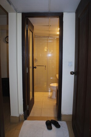 A doorway leading to a bathroom with a toilet and a shower. - Hotel Royal Lahore (Lahore)