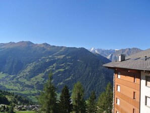 A mountain landscape with a building featuring a sloped roof and multiple windows.