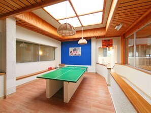 A room with a ping pong table, a large window, and a blue accent wall.