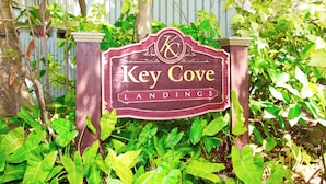 Ein hölzernes Schild mit der Aufschrift 'Key Cove Landings', umgeben von üppigem Grün.