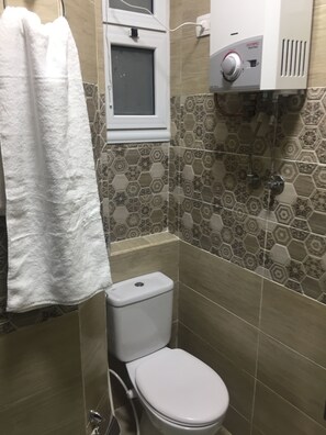 Un baño pequeño con inodoro, una toalla colgada en la pared y un calentador de agua.