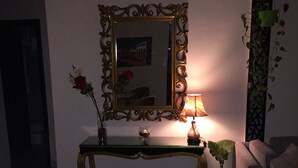 Ein Wohnzimmer mit einem Konsolentisch, einer Lampe, einem Spiegel und einem Blumentopf.