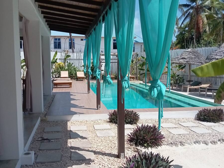 A covered outdoor area with a swimming pool, stone steps, and potted plants.