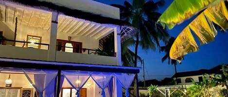 Un edificio de dos pisos con piscina, mobiliario exterior y un patio cubierto.