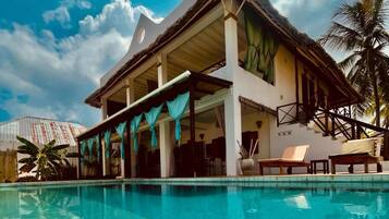 Relax by the resort's large pool, surrounded by palm trees and a tropical atmosphere.
